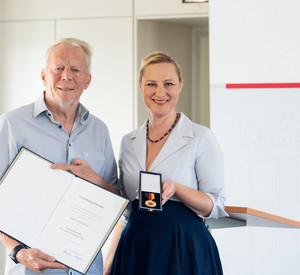 Werner Krebs und Ministerin Dörte Schall halten Urkunde und Verdienstmedaille